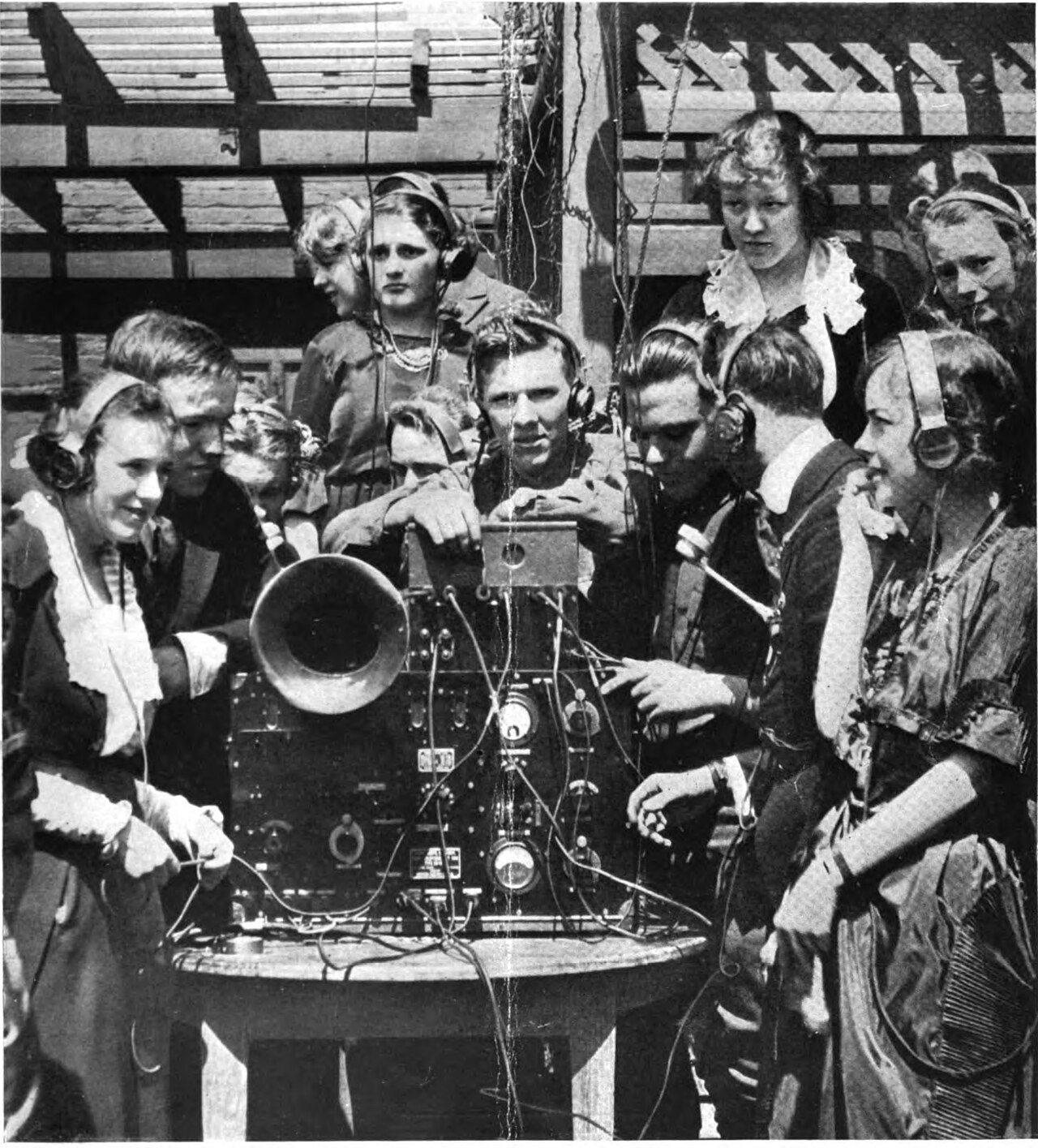 Young people wearing early radio earphones around a radio set, 1920